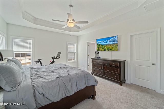 bedroom with a ceiling fan, visible vents, a tray ceiling, ornamental molding, and light carpet