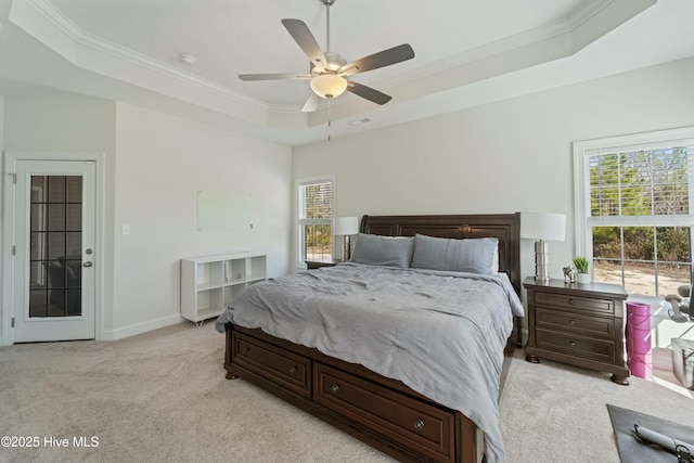 bedroom with crown molding, baseboards, light colored carpet, a tray ceiling, and a ceiling fan