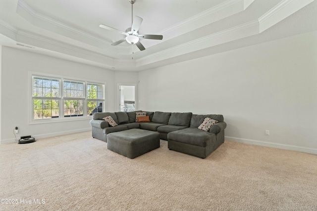 carpeted living room with visible vents, a raised ceiling, ornamental molding, a ceiling fan, and baseboards