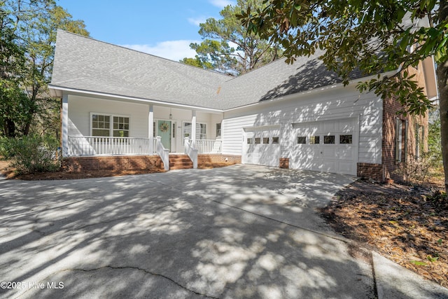 view of front of house featuring a garage, covered porch, driveway, and a shingled roof