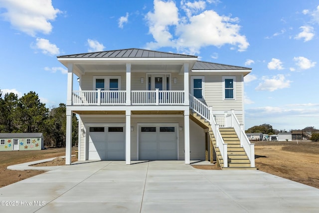 beach home with a porch, concrete driveway, stairs, and a standing seam roof