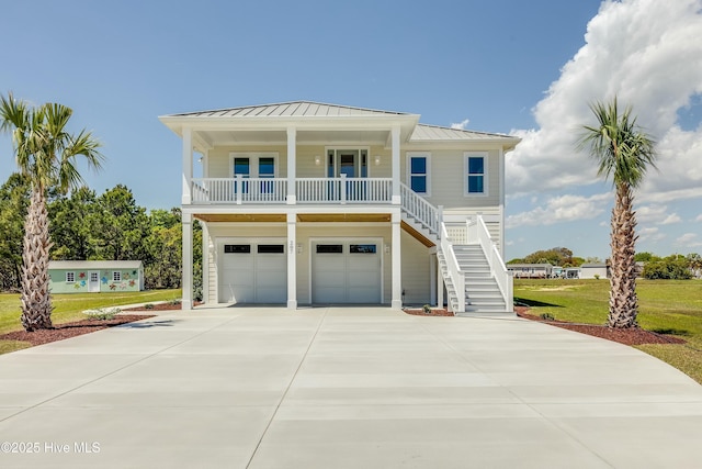 coastal home with a standing seam roof, driveway, covered porch, metal roof, and stairs