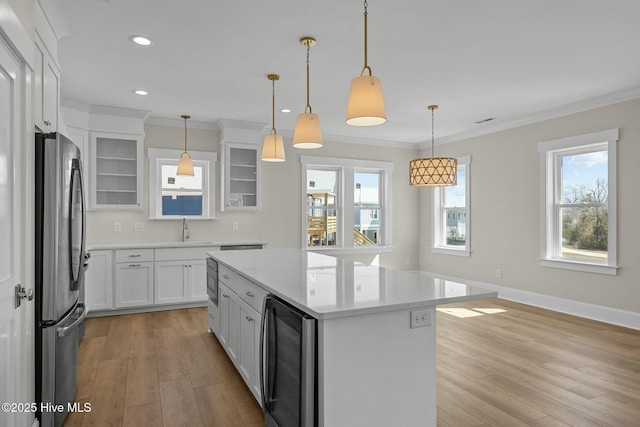 kitchen with light wood-style floors, beverage cooler, crown molding, and freestanding refrigerator