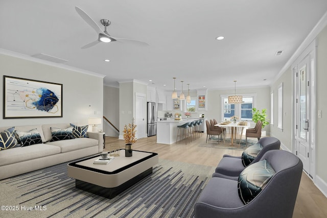 living area with recessed lighting, visible vents, crown molding, and light wood finished floors