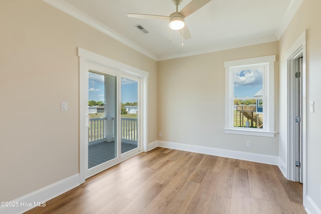 spare room featuring light wood-type flooring, baseboards, visible vents, ceiling fan, and crown molding