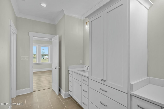 bathroom featuring vanity, tile patterned floors, crown molding, and baseboards