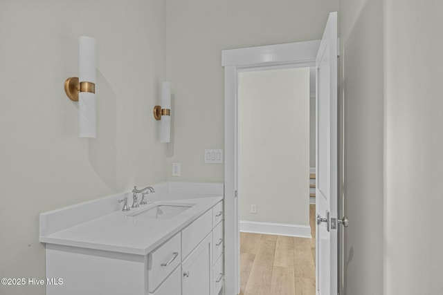 bathroom with vanity, wood finished floors, and baseboards