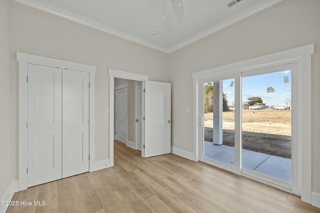 unfurnished bedroom featuring access to exterior, crown molding, baseboards, light wood-style flooring, and a closet