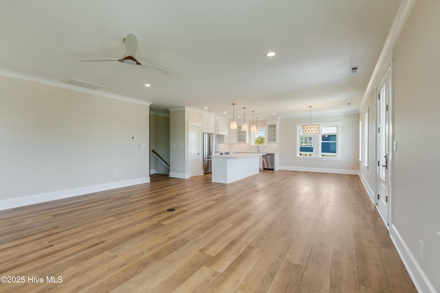 unfurnished living room featuring light wood-style flooring, baseboards, recessed lighting, and crown molding