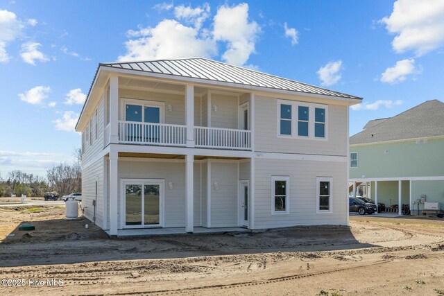 rear view of house with a balcony, metal roof, and a standing seam roof