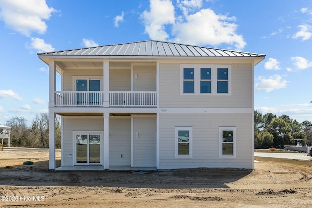 back of house with metal roof, a balcony, and a standing seam roof