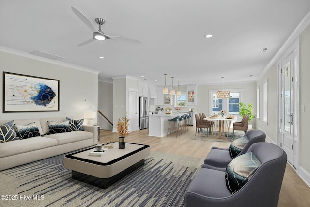 living area featuring recessed lighting, ornamental molding, visible vents, and light wood-style flooring