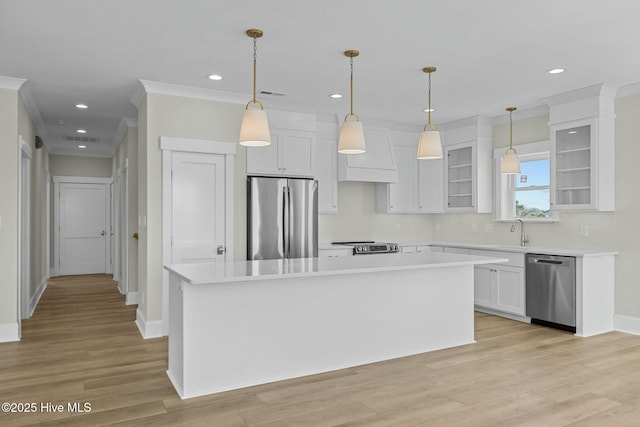 kitchen with a sink, light countertops, white cabinets, appliances with stainless steel finishes, and a center island