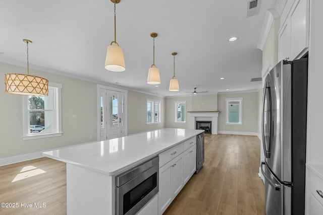 kitchen featuring visible vents, light wood finished floors, stainless steel appliances, white cabinetry, and open floor plan