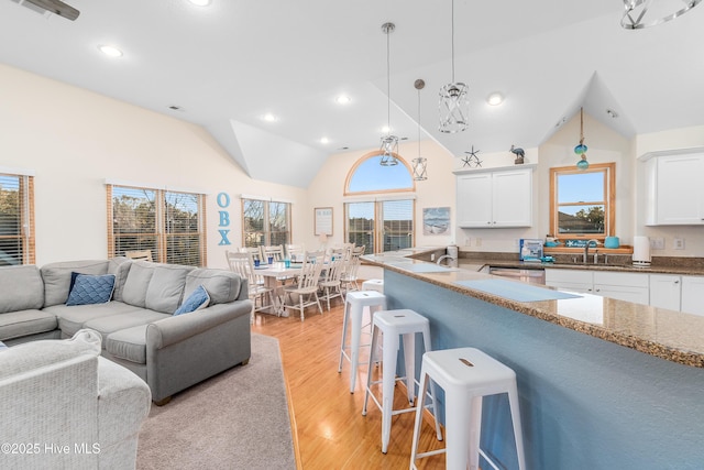 kitchen with light wood-style floors, a breakfast bar, open floor plan, and white cabinets