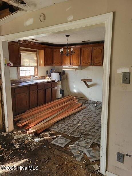 kitchen with a chandelier, decorative light fixtures, water heater, brown cabinets, and a sink