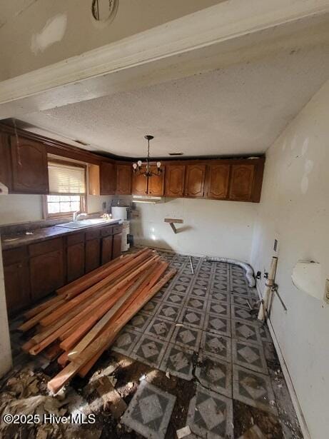 kitchen with decorative light fixtures, a textured ceiling, dark countertops, and a sink