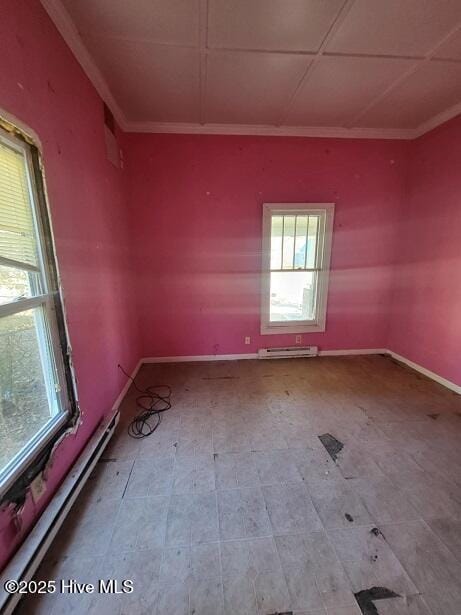 spare room with a baseboard heating unit, crown molding, and baseboards