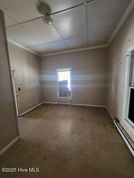 spare room featuring crown molding, baseboards, and a baseboard radiator