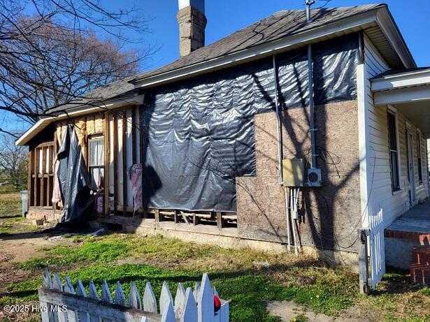 view of side of property featuring fence and a chimney