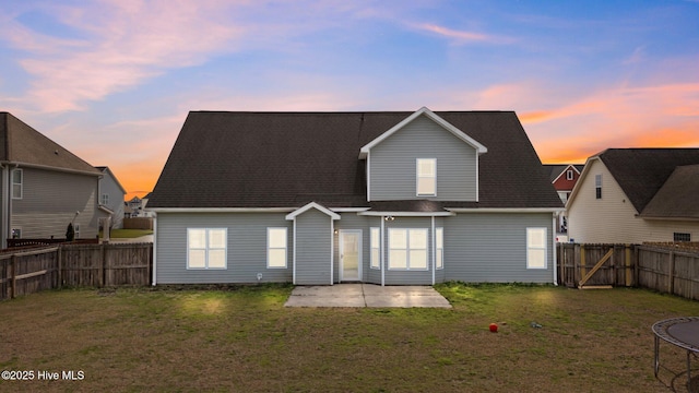 rear view of house featuring a lawn, a trampoline, a fenced backyard, and a patio area