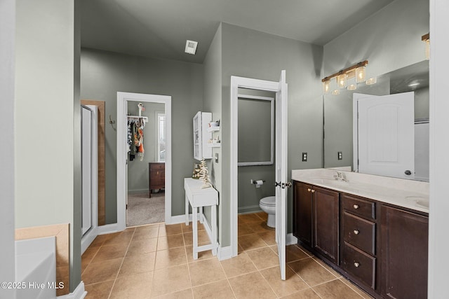 full bath featuring double vanity, a stall shower, a sink, tile patterned flooring, and toilet