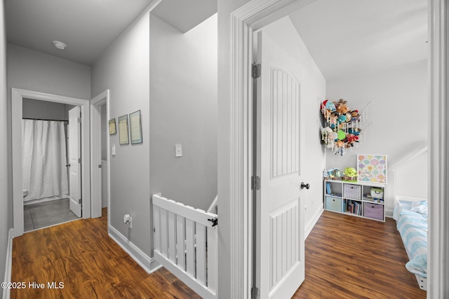 corridor with an upstairs landing, baseboards, and wood finished floors