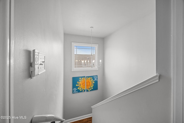 stairway featuring baseboards and an inviting chandelier