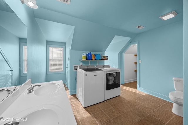 full bathroom with visible vents, washing machine and clothes dryer, a sink, vaulted ceiling, and toilet