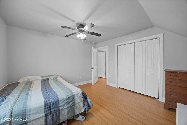 bedroom featuring baseboards, light wood finished floors, ceiling fan, vaulted ceiling, and a closet