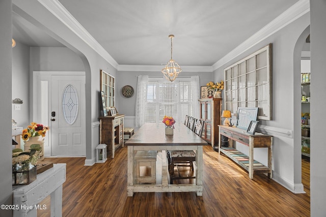 dining room with an inviting chandelier, wood finished floors, arched walkways, and ornamental molding