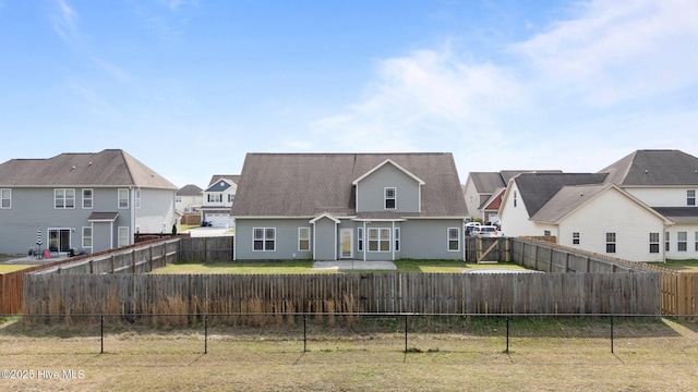 back of property with a yard, a residential view, and a fenced backyard