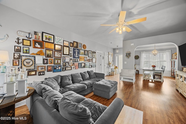 living area featuring arched walkways, wood finished floors, and a ceiling fan