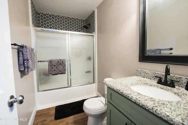 bathroom featuring toilet, shower / bath combination with glass door, vanity, and wood finished floors