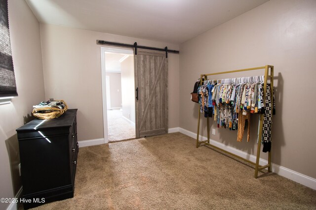 interior space featuring baseboards, a barn door, and carpet floors