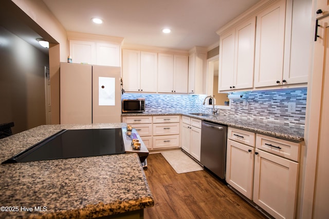 kitchen with stone countertops, dark wood-style flooring, a sink, decorative backsplash, and appliances with stainless steel finishes