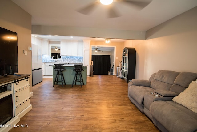 living room with light wood-type flooring and ceiling fan