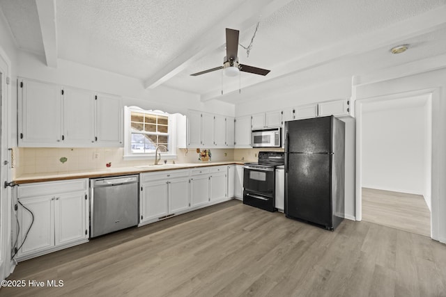 kitchen featuring beam ceiling, white cabinets, black appliances, and a sink