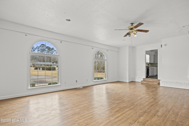 unfurnished living room featuring baseboards, a textured ceiling, light wood-type flooring, and a ceiling fan