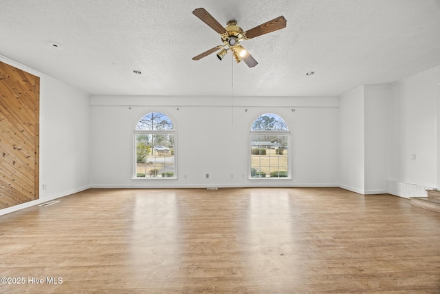 unfurnished living room featuring a ceiling fan, light wood-style floors, a wealth of natural light, and a textured ceiling