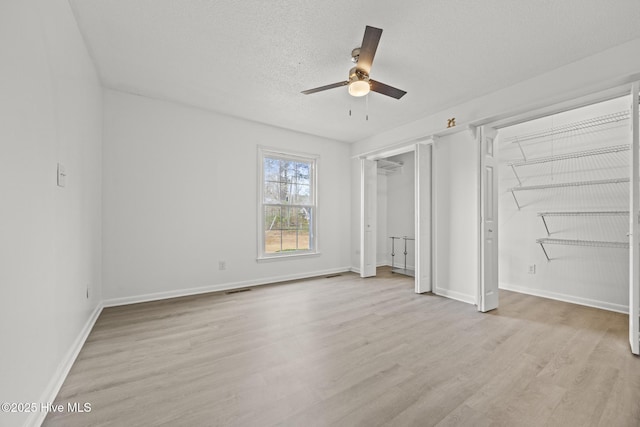 unfurnished bedroom with visible vents, baseboards, light wood-style flooring, a textured ceiling, and a ceiling fan