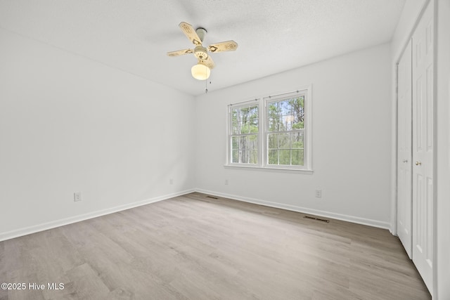 unfurnished bedroom featuring a closet, visible vents, baseboards, and wood finished floors