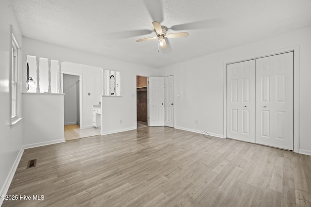 unfurnished bedroom with two closets, visible vents, baseboards, and light wood finished floors