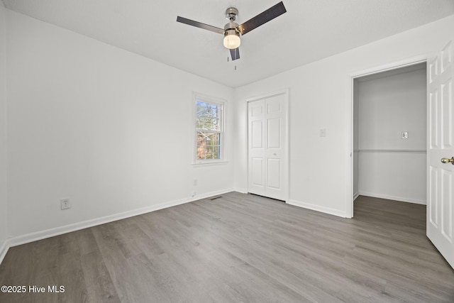 unfurnished bedroom featuring a closet, ceiling fan, baseboards, and wood finished floors