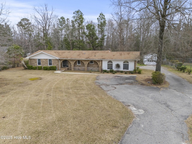 single story home with aphalt driveway, brick siding, a front yard, and a chimney