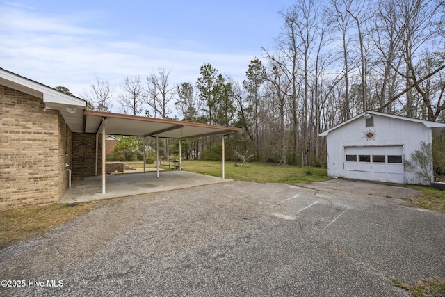 view of parking / parking lot with aphalt driveway, a detached garage, and a carport