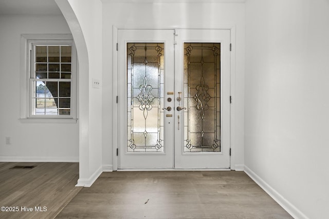 foyer entrance with visible vents, baseboards, french doors, wood finished floors, and arched walkways