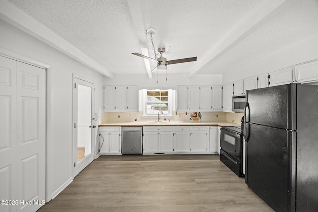 kitchen with light wood-type flooring, black appliances, light countertops, and white cabinetry