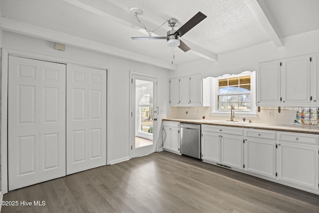 kitchen with dishwasher, beam ceiling, wood finished floors, white cabinets, and a sink