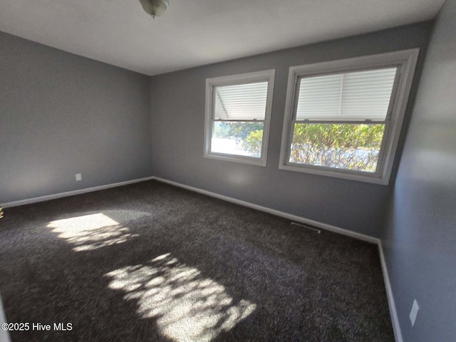 carpeted spare room featuring baseboards and visible vents